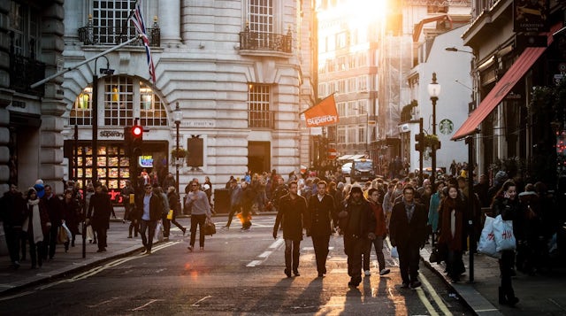 Groups of people walking past shops through central London