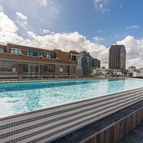 Swim lengths in the heated rooftop pool with skyline views over the city