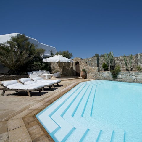 Relax with a cocktail on a sun lounger by the private outdoor pool