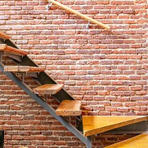 Admire the old workshop-like touches like the exposed brick wall and wooden steps