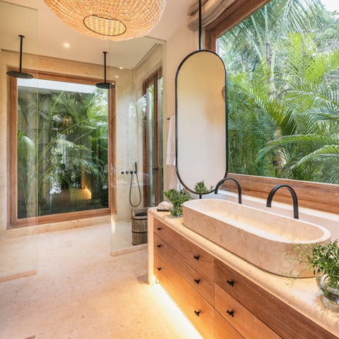 Shower surrounded by vivid foliage with large windows, natural light and luxuious rainfall showers