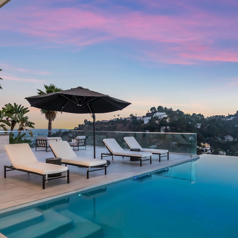 Lounge by the infinity pool with a cold drink as the sun sets over the hills