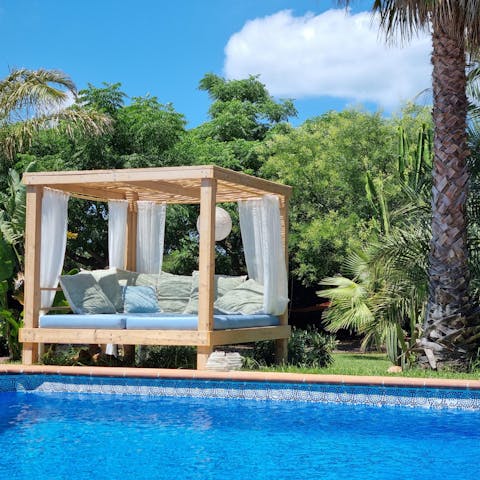 Laze beside palm trees in your garden daybed before dipping in the pool
