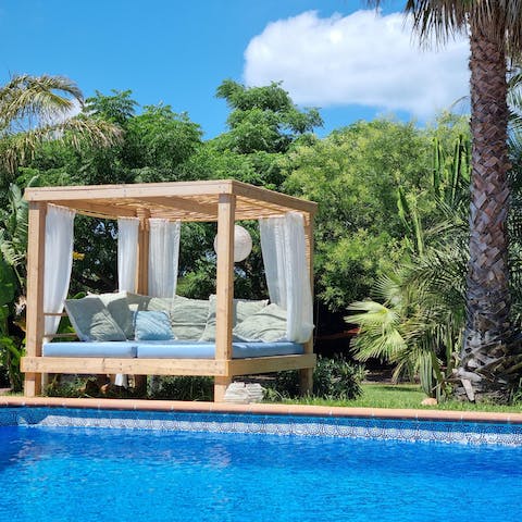 Laze beside palm trees in your garden daybed before dipping in the pool