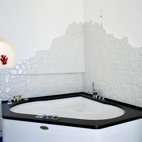 Treat yourself to a relaxing soak in this corner jacuzzi tub