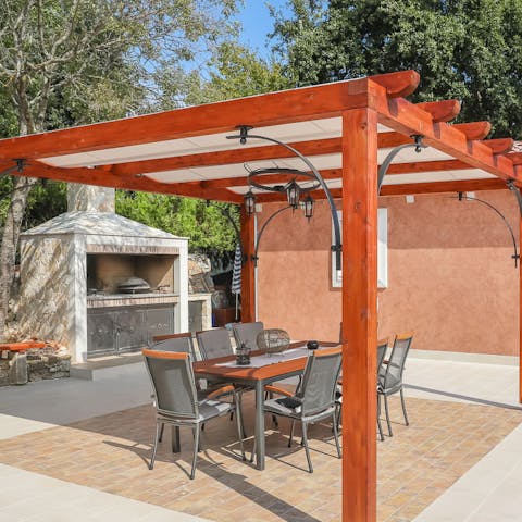Grill up a feast on your outdoor barbecue and enjoy it alfresco at the gazebo's elegant dinner table