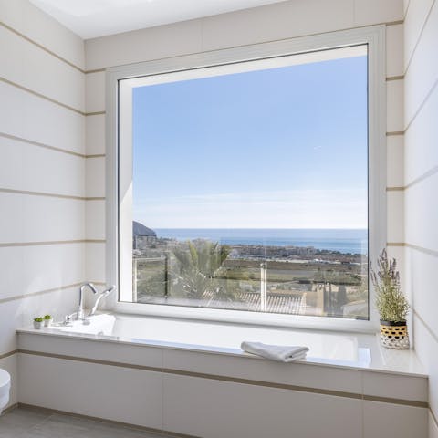 Pour a bath by the large window which frames the townscape of Moraira well