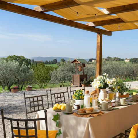 Dine beneath the pergola as the Tuscan countryside stretches out before you