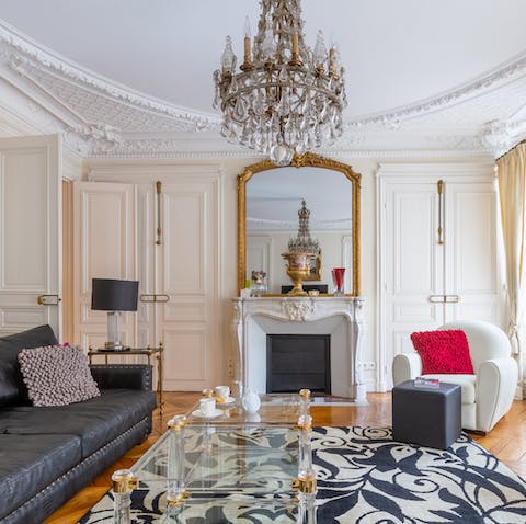 Relax in the opulent living room under chandelier and ornate cornicing