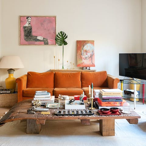 Curl up on the statement orange sofa, surrounded by eye-catching artwork and fascinating books