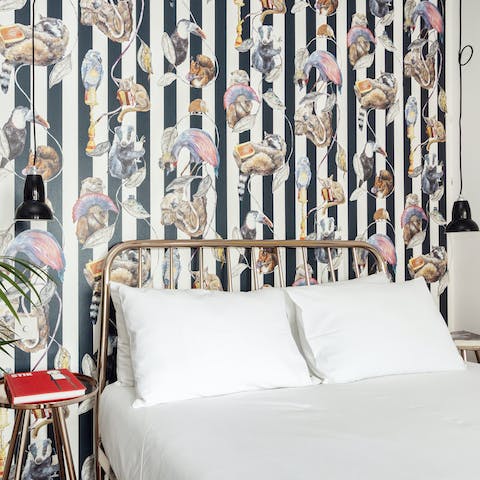 Admire the patterned wallpaper before falling asleep in the metal-framed bed