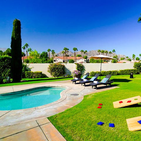 Jump into the swimming pool and dry off as you play cornhole