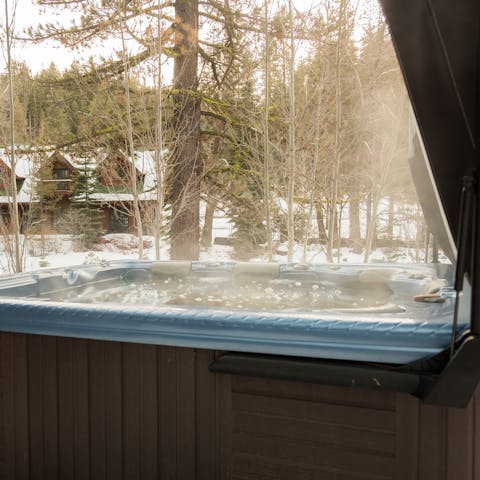 Soak in the heat of the hot tub as snow falls around you