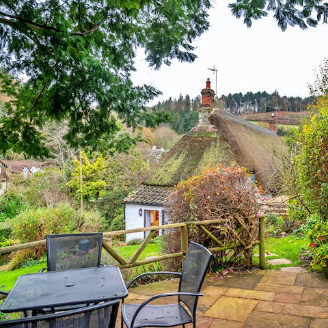 Enjoy a cup of tea out on the elevated patio terrace with views over the charming cottage and garden