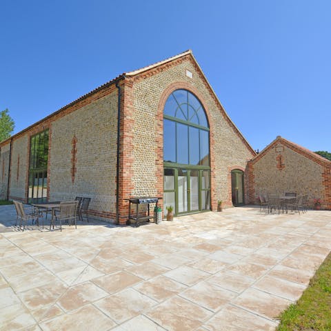 Dine alfresco on the sun-drenched terrace with tranquil views over the lawn