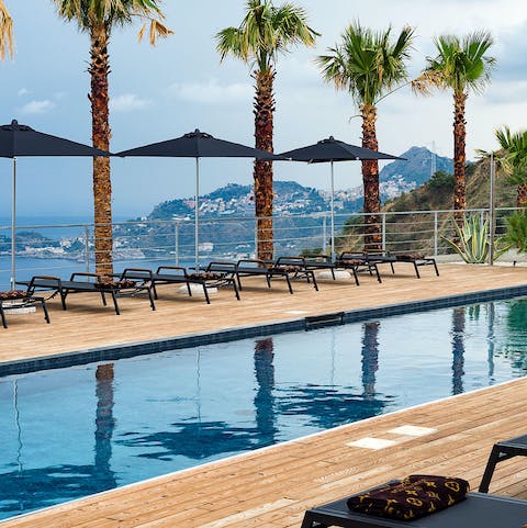 Swim in the pool lined with palm trees and a spectacular view