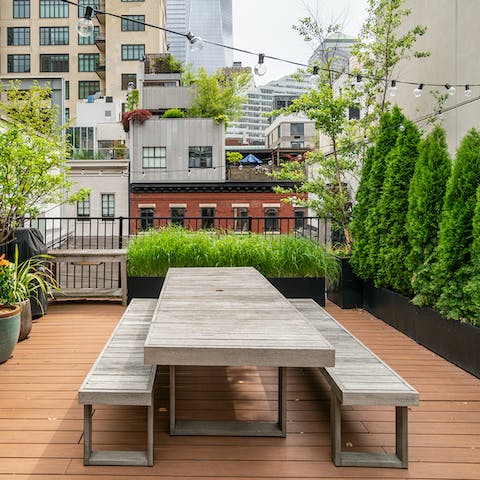 Enjoy a barbecue on the rooftop terrace with its dining table, sofa, verdant shrubs and pretty string lights