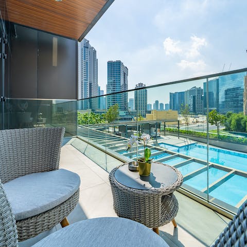 Relax and unwind out on your private balcony with stunning views of the pool and the cityscape beyond  