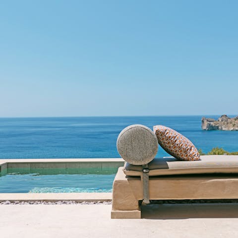 Relax on a daybed by the private pool and take in the sea views