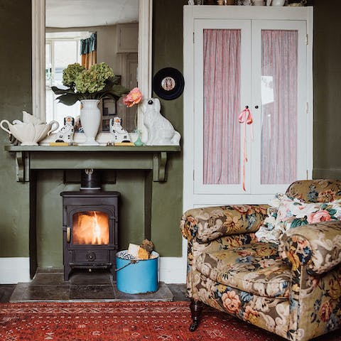 Lounge in the cushy floral armchair and get cosy in front of the wood burner