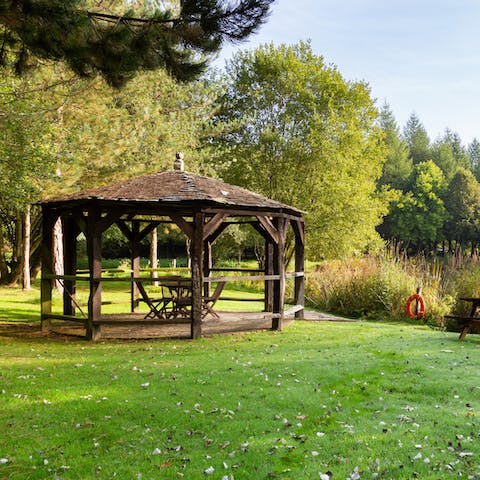Read by the river under the shade of the wooden gazebo