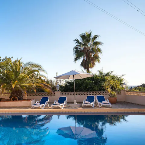 Relax on a lounger by the private outdoor swimming pool