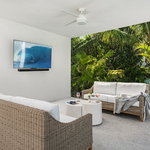 Watch your favourite movies on the wall-mounted TV in the outdoor lounge area