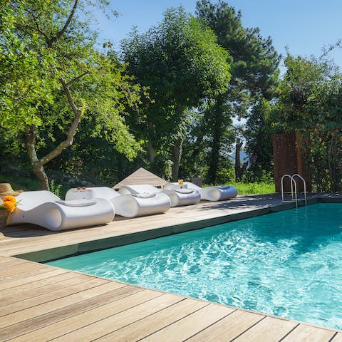 Relax in paradise by the private outdoor pool on one of the modern sun loungers