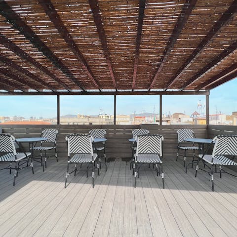 Set up for sunset drinks on the shared rooftop terrace with a city view