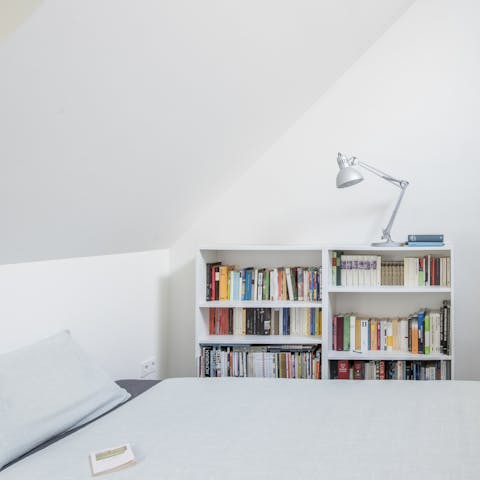 Cosy up in the minimalist bedroom with one of the many books from the shelves