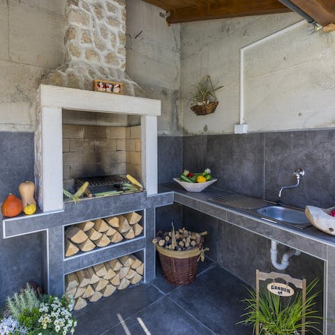 Prepare dinner in the outdoor kitchen before grilling it over the wood-fired barbecue