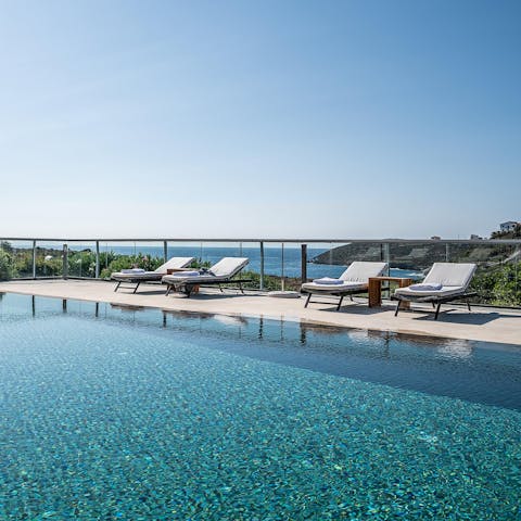 Lounge around the swimming pool with views of the Mediterranean Sea in the background 