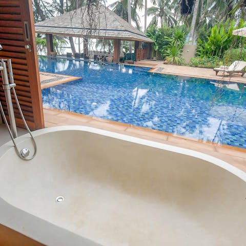 Soak in the sleek bathtub overlooking the pool area 