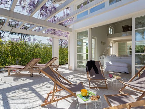 Lounge in the sun on the outdoor terrace, covered in blooming wisteria