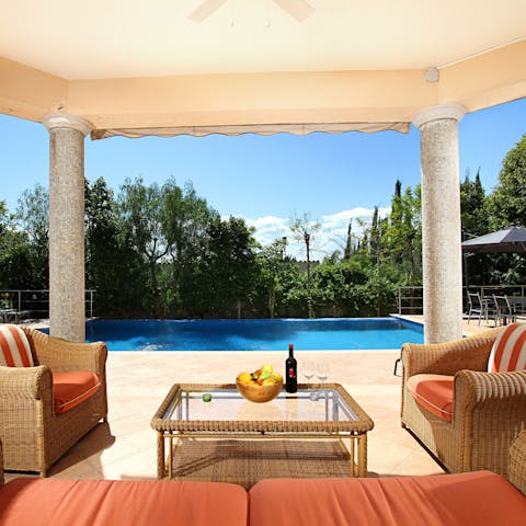 Relax in the shade of the covered terrace by the pool with glasses of red wine