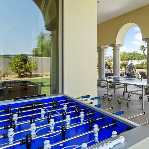 Play foosball with the tranquil setting of the garden in the background 