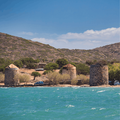 Explore ancient windmills along the rocky coastline of Elounda