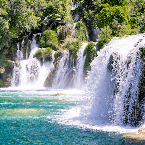 Swim beneath cascading waterfalls in Krka National Park, a twenty-five-minute drive away