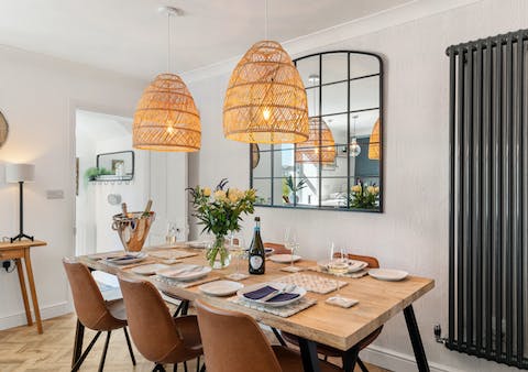 Gather around the chic dining table for dinners at home, the warm-toned light fixtures setting the mood