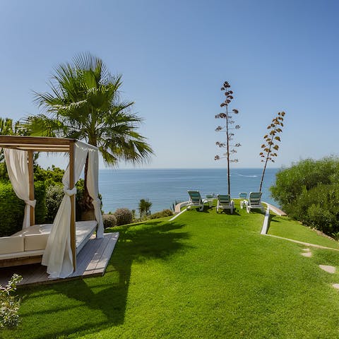 Soak up the stunning sea views from a day bed in the lush gardens