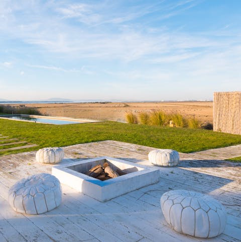 Toast marshmallows around the fire pit while the sun sets over the fields