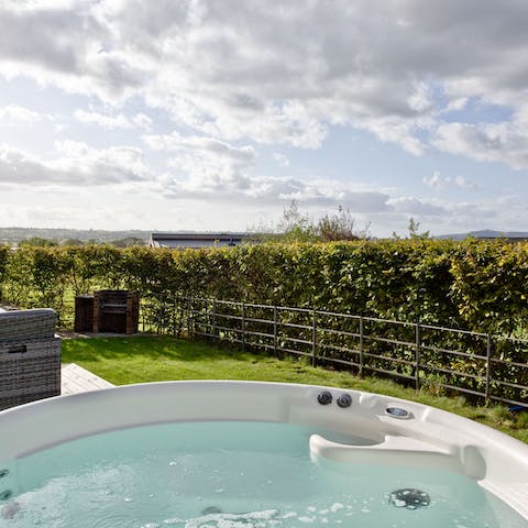 Soak in the hot tub as the sun sets over the hills