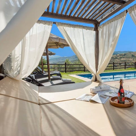 Hide from the sun on the four poster daybed by the pool
