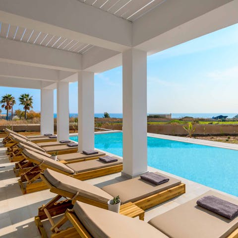 Laze on luxe loungers beside the pool while gazing out to sea