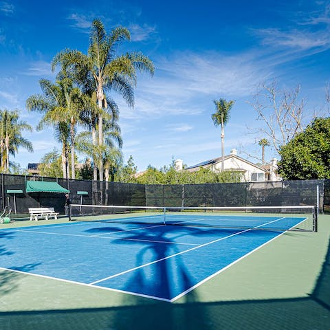Play a game of tennis surrounded by palm trees
