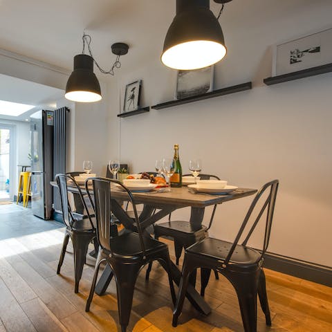 Gather around the dining table for a relaxed evening of home-cooked meals and drinks, with the low-hanging light fixture setting the ambience