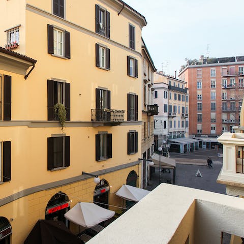 Stand on the balcony with a drink in hand amidst the charming Milan street setting