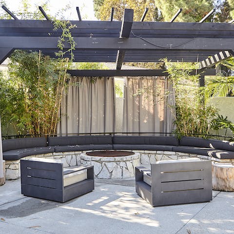 Gather around the firepit under the wooden pergola