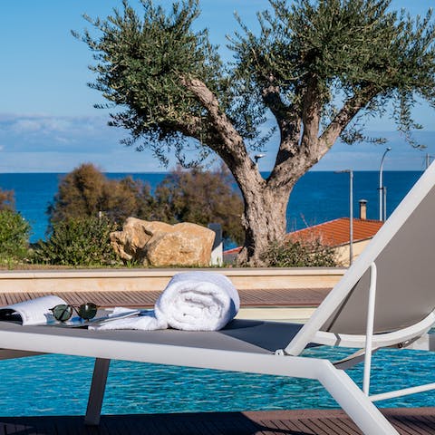 Soak up the rays on your poolside sun lounger that features stunning views out to sea