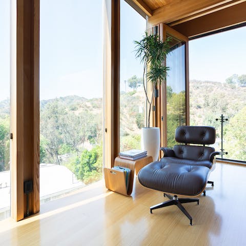 Relax in the elegant Eames chair by the floor-to-ceiling glass walls 